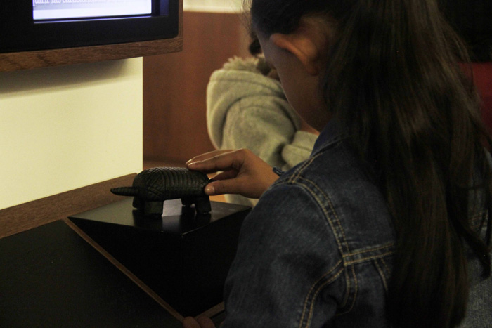 Niña tocando una de las piezas táctiles de la sala Tierra como Recurso 