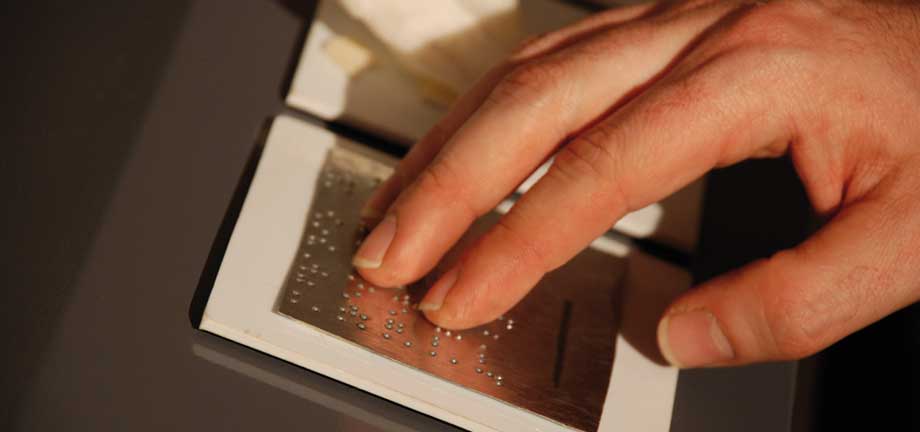 Lectura en braille. Fotografía de las manos de un hombre.