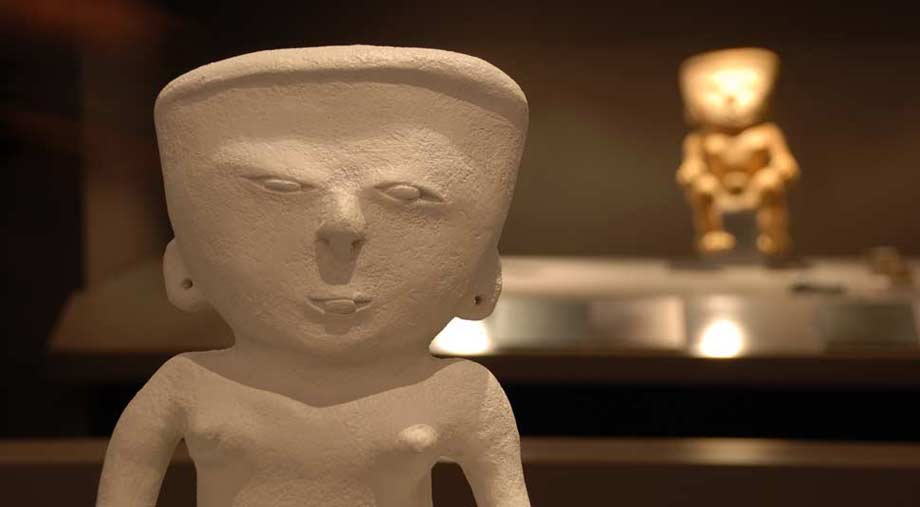 Fotografía de la réplica de una figura precolombina, con pieza original al fondo.