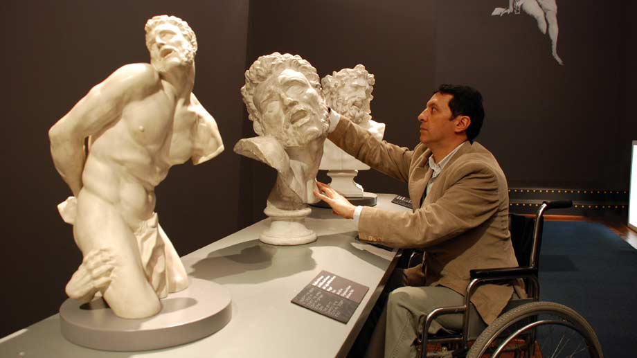 Hombre en silla de ruedas toca las réplicas de las esculturas
